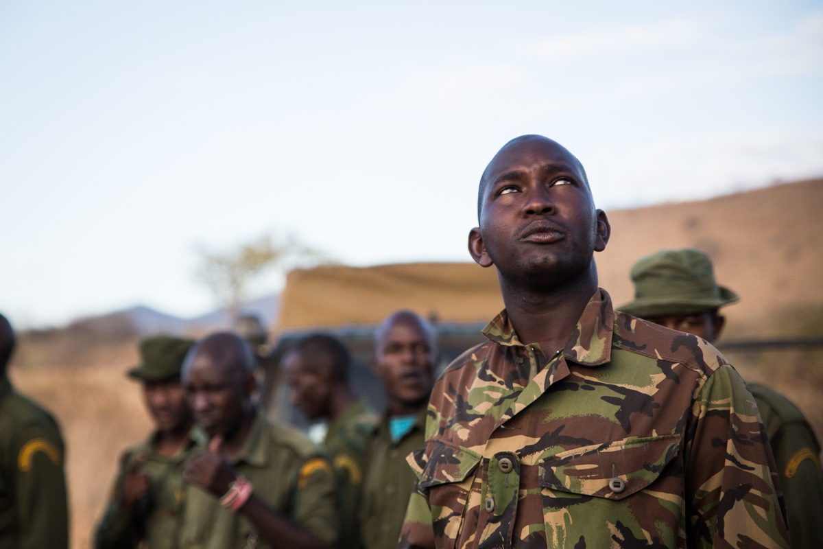 Wildlife ranger looking up at spotter plane. Chyulu Hills, Kenya.