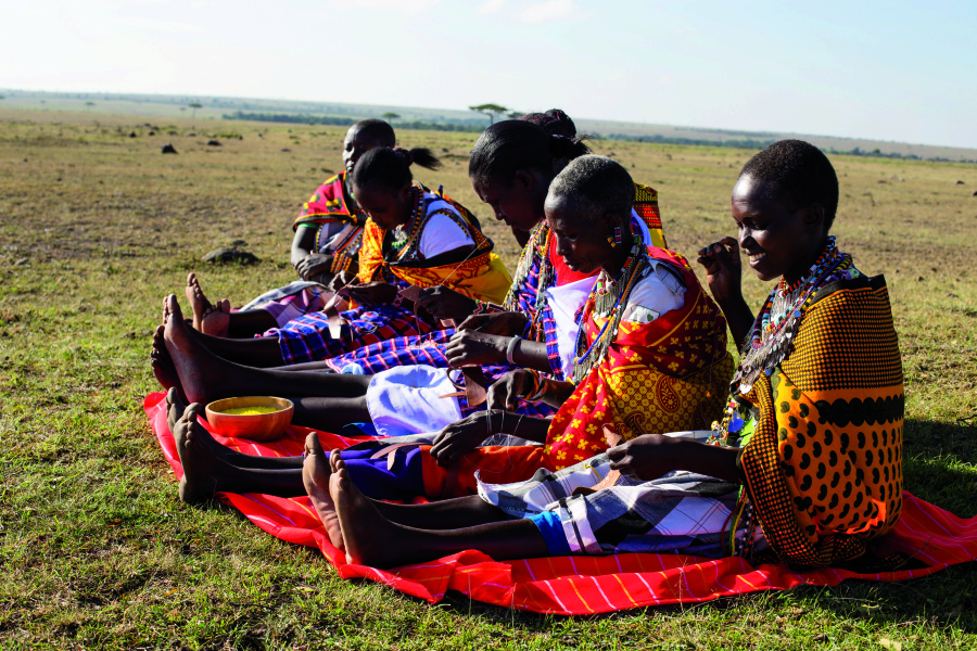 A group of Maasai women beading - chatting and laughing as they go.